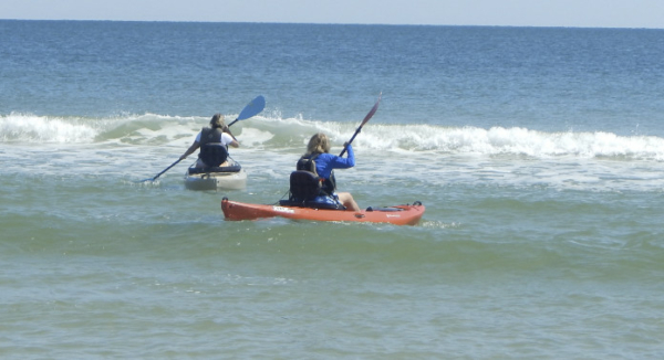 People kayaking on the beach waves.